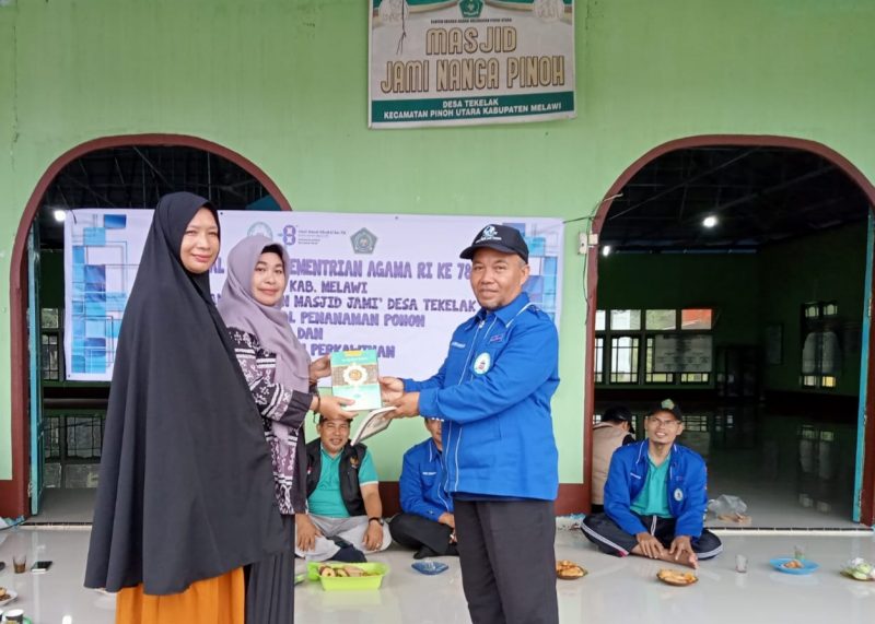 Ketua Asosiasi Penghulu Republik Indonesia (APRI) Kabupaten Melawi, H. Darwisno membagikan mushaf Al-Qur'an dalam momen acara bhakti sosial penanaman pohon produktif dan Penyuluhan Perkawinan 